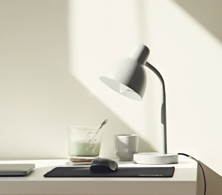 Un bureau avec une lampe et une tasse, dans le soleil du matin.